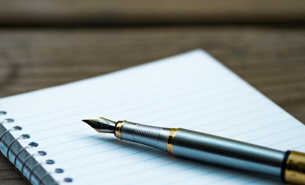 The text "Write With Wendy" beneath a flower attached to a fountain pen tip.